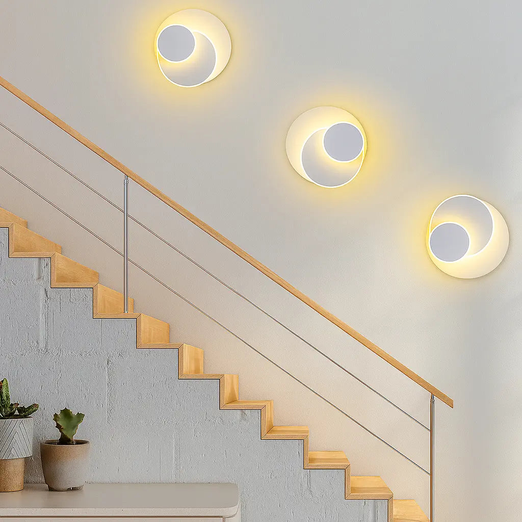 Two ORLUNE HOME LED wall sconces cast a soft, modern yellow glow on the staircase.