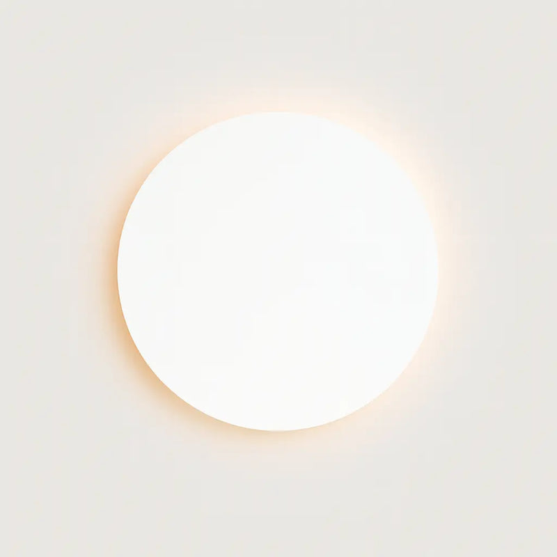 Soft, warm halo lighting radiates from the ORLUNE HOME minimalist black round LED wall light.
